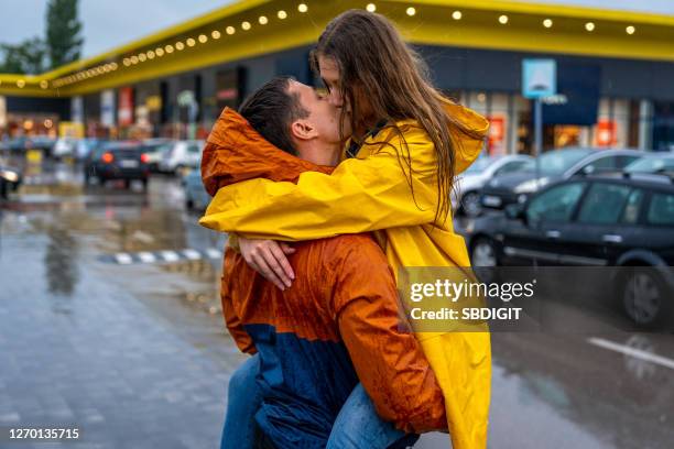 jeune couple embrassant sur la pluie - couples kissing shower photos et images de collection