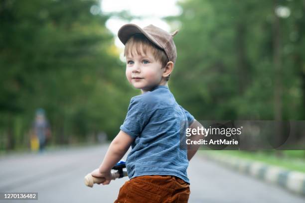 cute little boy riding a bycicle in a park in summer - boy looking over shoulder stock pictures, royalty-free photos & images