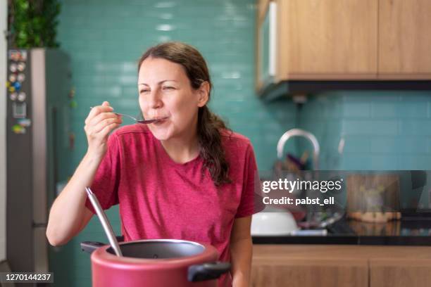 mujer degustación de comida cocida en cuchara de cocina - bean fotografías e imágenes de stock