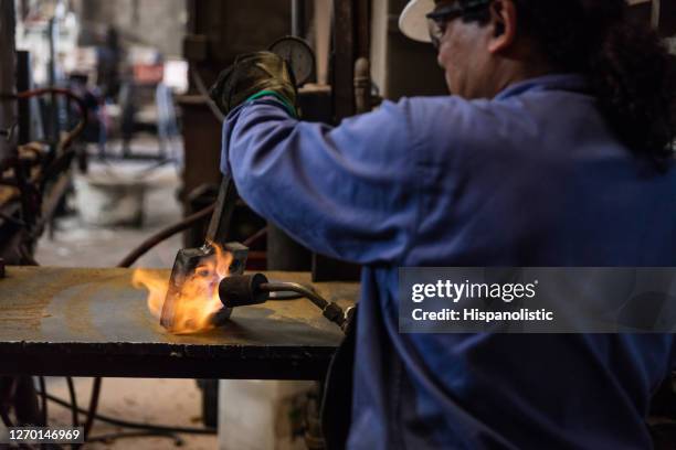 latin american blue collar worker at a metallurgic workshop using a blowlamp - blowlamp stock pictures, royalty-free photos & images
