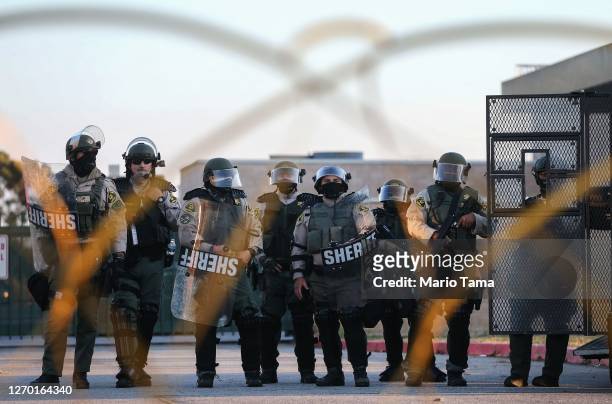 Los Angeles sheriff's deputies keep watch at the South Los Angeles Sheriffs' station as protesters demonstrate nearby against the death of Dijon...
