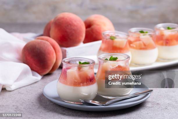 homemade panna cotta with slices of peach and peach jelly in glass jars on a gray concrete background. - panna cotta imagens e fotografias de stock