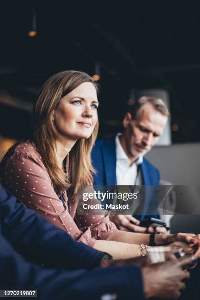 female entrepreneur sitting with male coworkers at workplace - work culture stockfoto's en -beelden