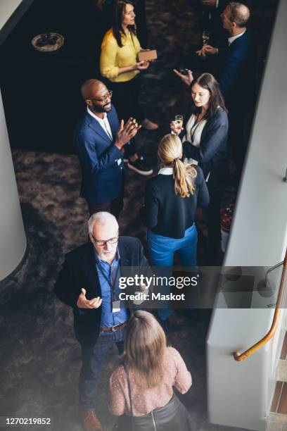 high angle view of male and female entrepreneurs discussing while standing in office - business networking event stock-fotos und bilder