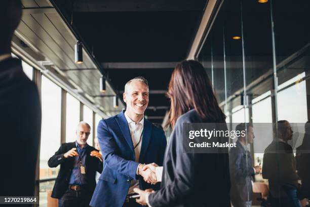 smiling male entrepreneur shaking hands with businesswoman at workplace - group of businesspeople standing low angle view stock pictures, royalty-free photos & images
