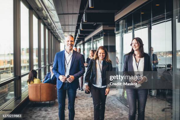 smiling businesswoman talking to coworker in corridor at workplace - congress seats stock pictures, royalty-free photos & images