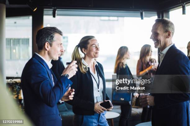 male and female colleagues discussing while standing at workplace - kongressversammlung stock-fotos und bilder