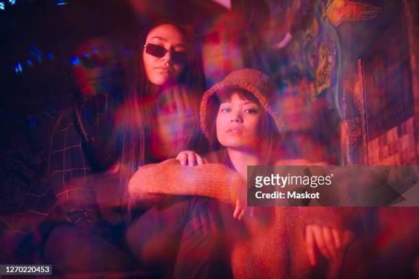 multiple exposure of young female friends sitting together at illuminated restaurant - double exposure stock pictures, royalty-free photos & images