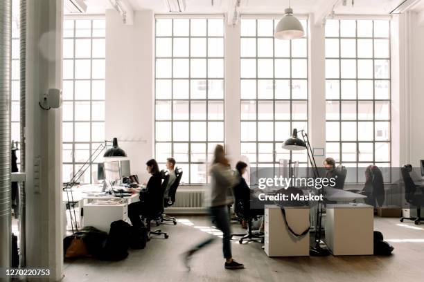 male and female professional coworkers working in office - blurry office stock-fotos und bilder
