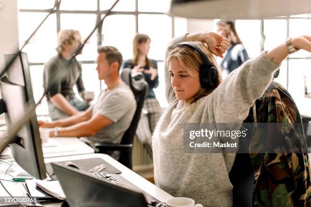 female entrepreneur stretching while looking at computer in office - yawn office stock pictures, royalty-free photos & images