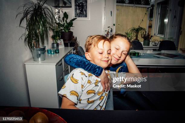 smiling girl embracing brother in living room - camera flashes foto e immagini stock