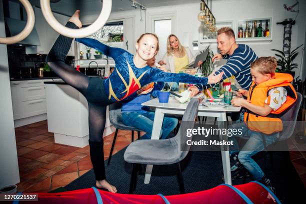 portrait of smiling girl exercising while family eating breakfast at table - bizarre fotografías e imágenes de stock