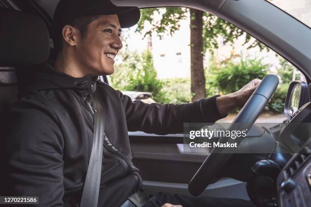 smiling delivery man driving truck - asian man sitting casual imagens e fotografias de stock