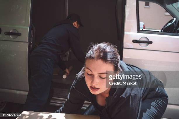 male and female delivery workers arranging package outside truck - unloading stock pictures, royalty-free photos & images