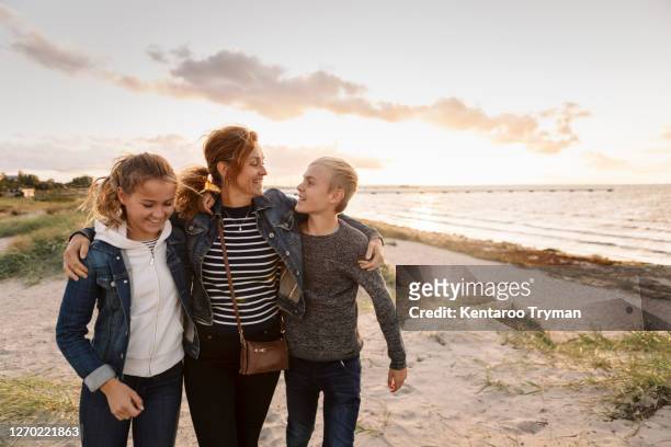 smiling mother and children at beach during weekend - boy and girl talking fotografías e imágenes de stock