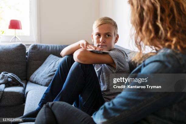 son talking to mother while sitting at home - sad boy stock-fotos und bilder