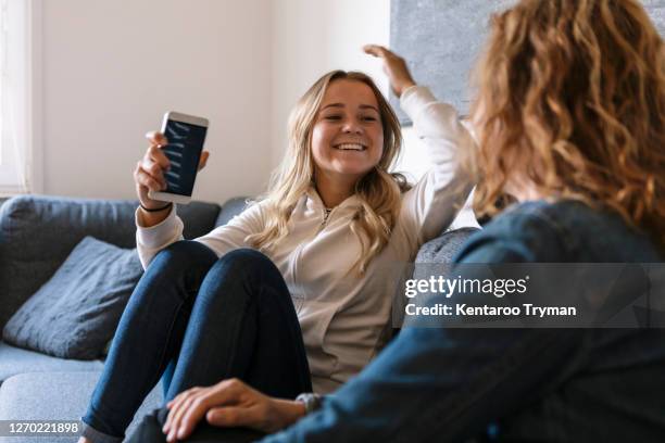 smiling daughter talking to mother while sitting at home - mother daughter couch imagens e fotografias de stock