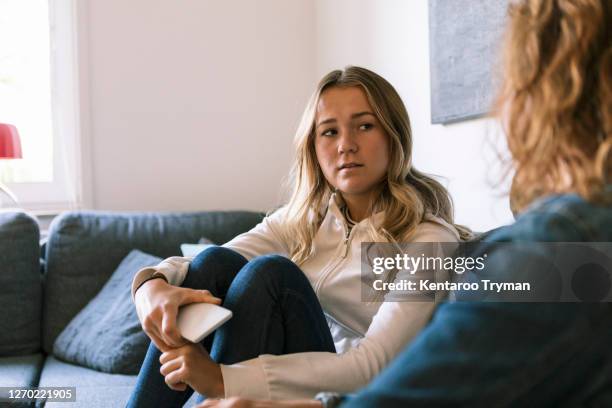 daughter talking to mother while sitting at home - mother daughter couch imagens e fotografias de stock