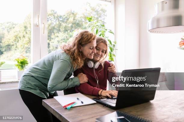 smiling mother embracing daughter at home - parent homework stock pictures, royalty-free photos & images