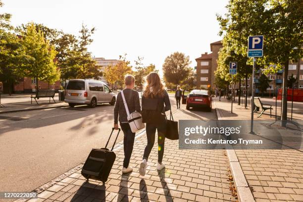 rear view of siblings with suitcase walking on roadside - single mother teen stock pictures, royalty-free photos & images