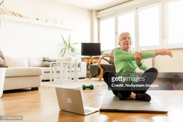 active senior woman home exercising with online coach - net sports equipment stock pictures, royalty-free photos & images