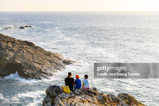 mother and her two sons sitting on a cliff looking at the ocean - folkestone stock pictures, royalty-free photos & images