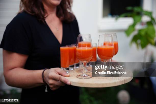 midsection of woman carrying wooden board with several drinking glasses filled with freshly made tomato gazpacho - gazpacho stock pictures, royalty-free photos & images