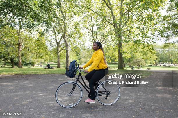 beautiful teenage girl riding a bike in a public park, wearing a yellow top - bike handle stock pictures, royalty-free photos & images