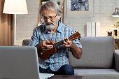 Man watching online tutorial, learning to play guitar.