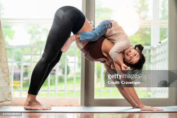 an asian  female yoga instructor workout together with her daughter or son in the living room with window light on yoga met - asian exercise stock-fotos und bilder