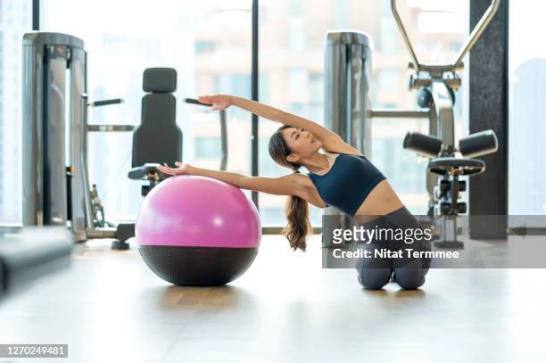 full length of asian young woman practicing advanced training on a pilates ball. gymnastics exercise. hotel fitness health club. - yoga ball work 個照片及圖片檔