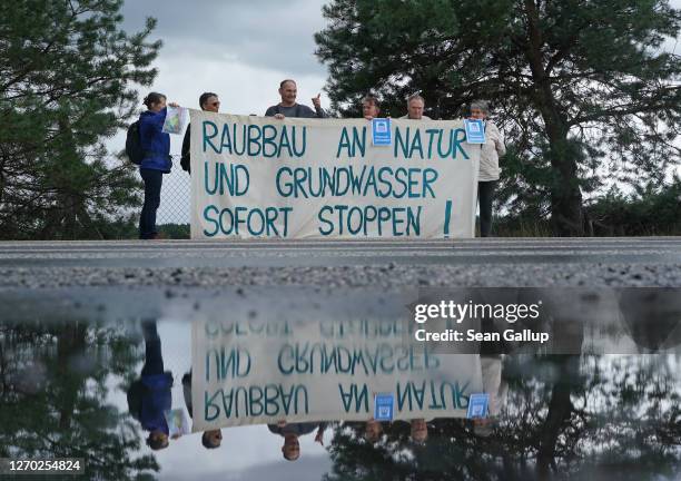 Protesters concerned over the future Tesla Gigafactory's effect on the local water table are reflected in a puddle as they protest at the...