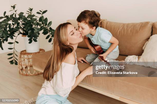 tween boy and mother playing guitar on sofa at home - toddler musical instrument stock pictures, royalty-free photos & images