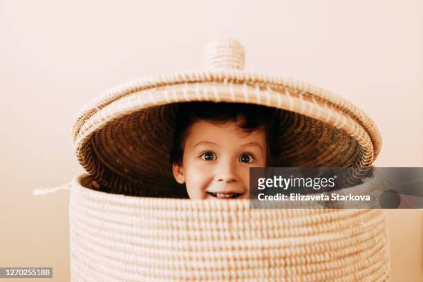 cheerful playful teen boy in wicker basket at home - toddler musical instrument stock pictures, royalty-free photos & images