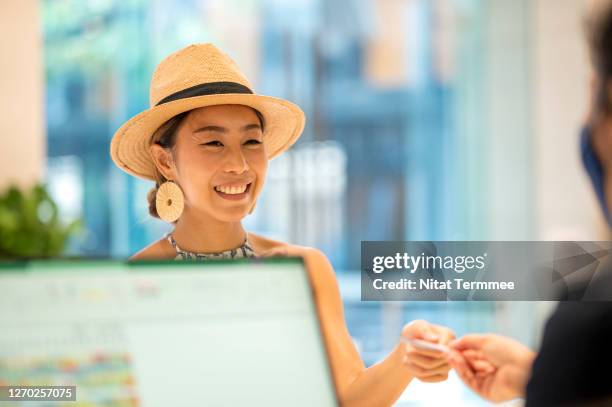 young asian women traveler, check in or paying at front desk. her receiving a hotel room key from customer service representative. - asian receptionist stock pictures, royalty-free photos & images