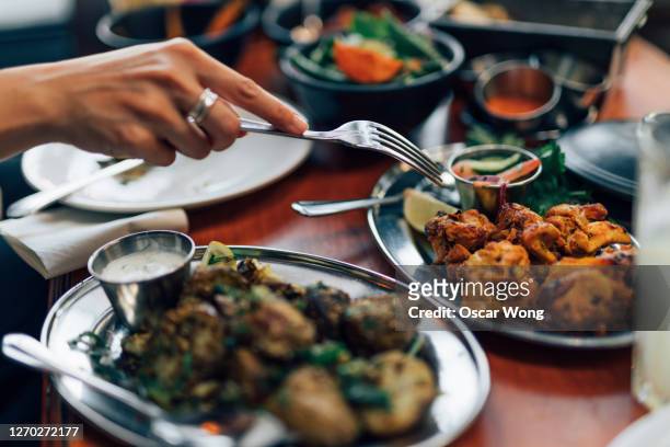 close up of woman eating chicken tikka with fork - serving dish stock-fotos und bilder
