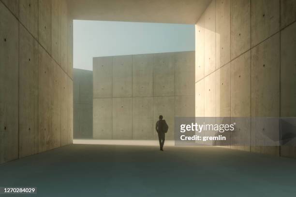 uomo d'affari che cammina in un corridoio di cemento - architettura foto e immagini stock