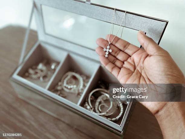 woman holds necklace with cross pendant - pendants foto e immagini stock