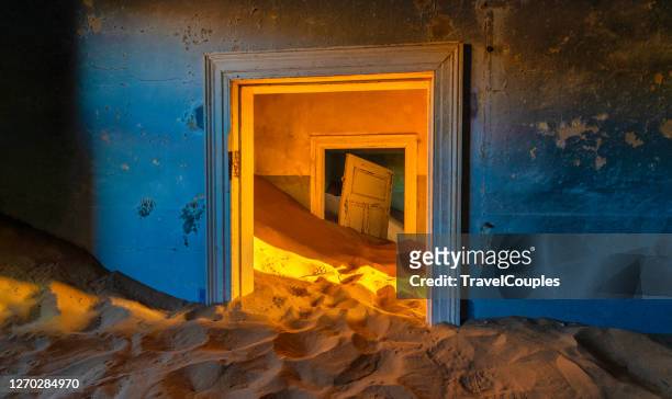 abandoned building being taken over by encroaching sand, kolmanskop ghost town, namib desert. an abandoned sand filled house with orange tones. kolmanskop, namibia - kolmanskop stock pictures, royalty-free photos & images