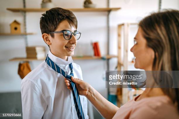 mother adjusting tie on school uniform of son - child getting dressed stock pictures, royalty-free photos & images