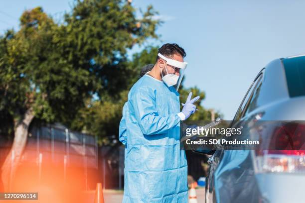 nurse gives instructions to patient at covid test site - drive through test stock pictures, royalty-free photos & images