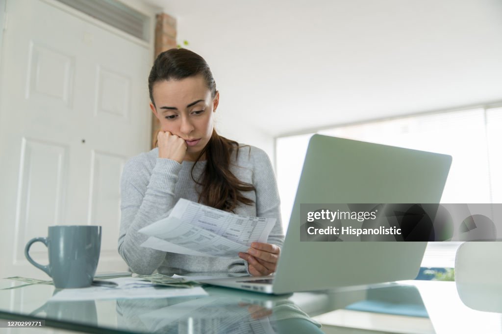 Woman paying her utility bills online and looking worried