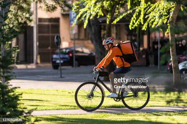 lebensmittellieferung auf dem fahrrad - bike messenger stock-fotos und bilder