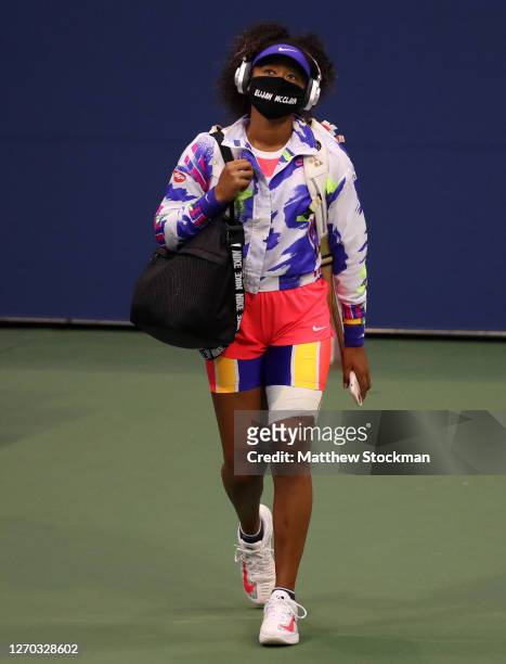 Naomi Osaka of Japan walks in wearing a mask with the name Elijah McClain on it before her Women’s Singles second round match against Camila Giorgi...