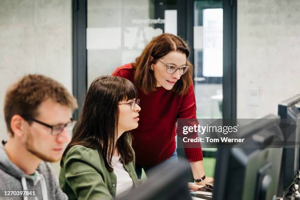 teacher helping student with computer work - professor da faculdade imagens e fotografias de stock