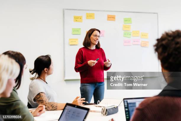 university tutor talking to class during seminar - kleine personengruppe stock-fotos und bilder