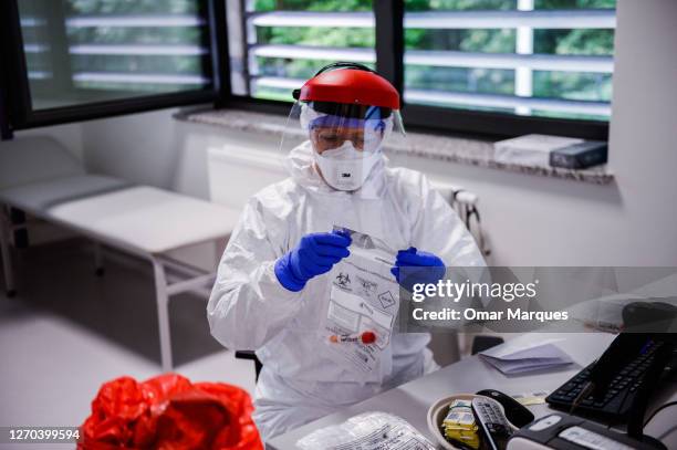 Doctor wears a protective suit , gloves and a face shield as she packs a COVID-19 swap sample for testing at the Krakow University Hospital on...