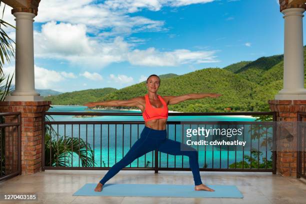 aantrekkelijke vrouw die op een privé dek bij een luxe villa uitoefent - private terrace balcony stockfoto's en -beelden