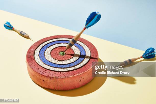 a dart in the bullseye of a dart board - colourful studio shots stockfoto's en -beelden