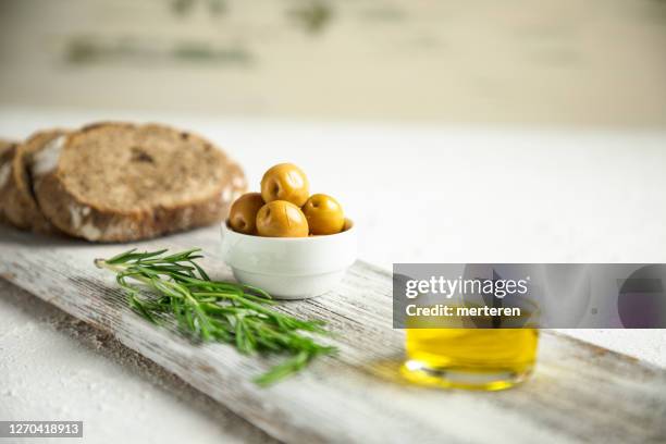 aceitunas y botellas de aceite de oliva sobre mesa rústica blanca - green olive fotografías e imágenes de stock